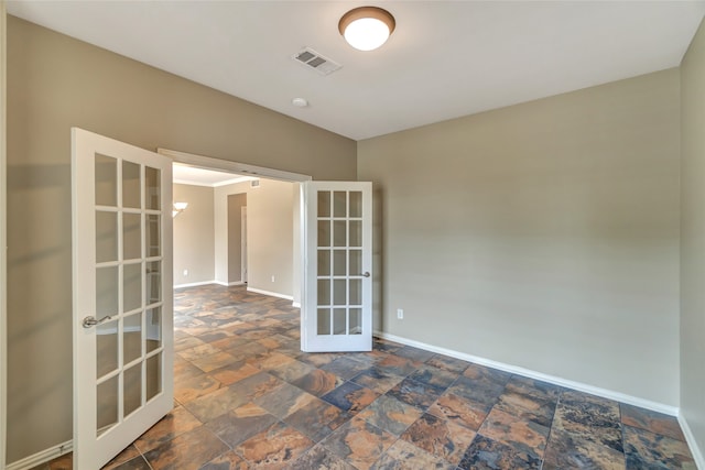 empty room featuring stone finish flooring, visible vents, baseboards, and french doors