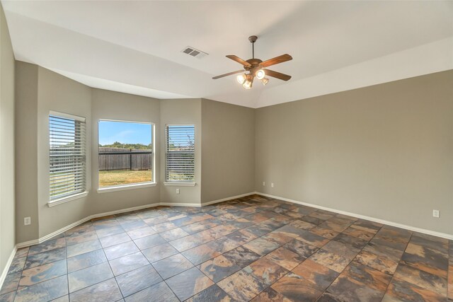 unfurnished room with visible vents, stone finish floor, vaulted ceiling, ceiling fan, and baseboards