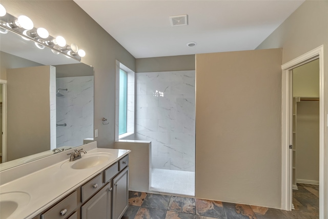 full bath featuring a marble finish shower, double vanity, a sink, and visible vents