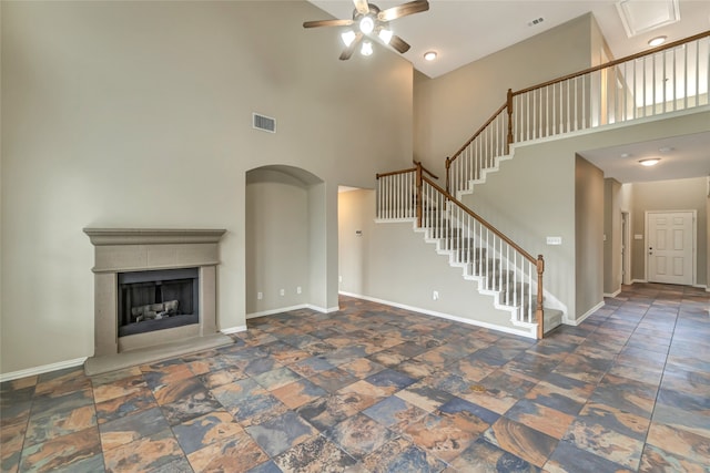 unfurnished living room with a towering ceiling and ceiling fan