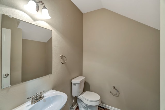 bathroom featuring lofted ceiling, a sink, toilet, and baseboards