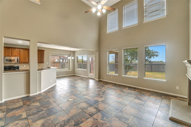 unfurnished living room featuring ceiling fan, a fireplace, and baseboards