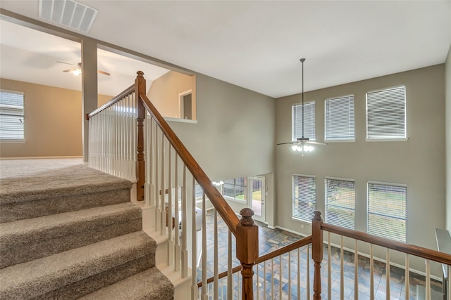 staircase featuring a ceiling fan, visible vents, and baseboards