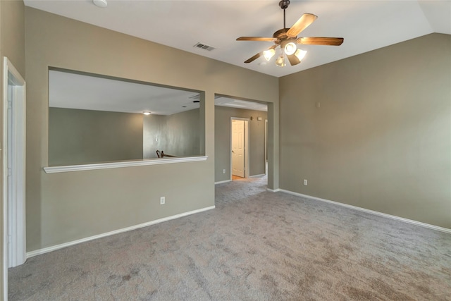 spare room featuring carpet, visible vents, a ceiling fan, vaulted ceiling, and baseboards