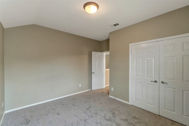 unfurnished bedroom with carpet floors, a closet, visible vents, vaulted ceiling, and baseboards