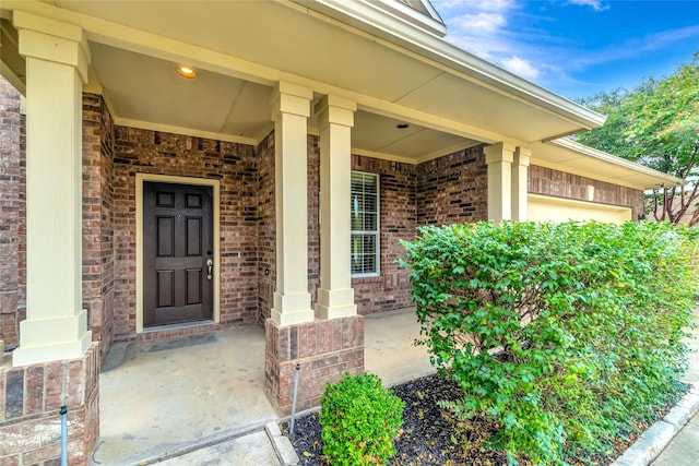 doorway to property featuring covered porch and brick siding