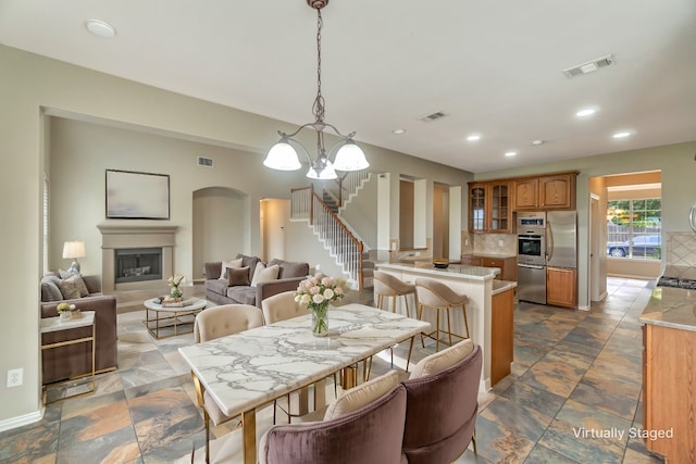 dining space with stairway, a glass covered fireplace, visible vents, and recessed lighting