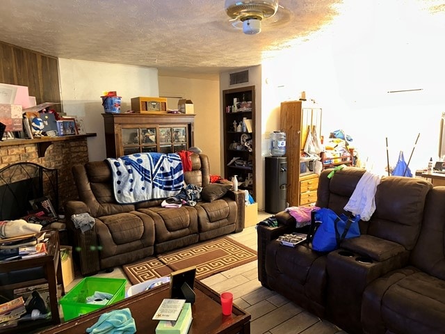 living room featuring ceiling fan, a textured ceiling, and light wood-type flooring