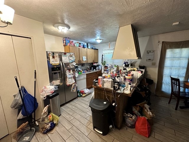 kitchen featuring a textured ceiling, dishwasher, light wood-type flooring, and stainless steel refrigerator with ice dispenser