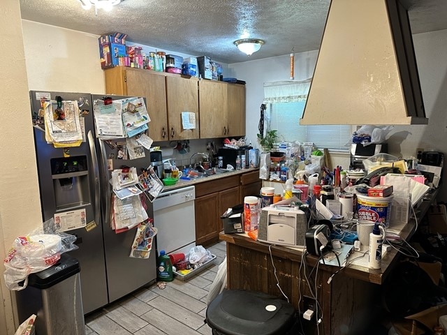 kitchen with stainless steel fridge with ice dispenser, a textured ceiling, light wood-type flooring, dishwasher, and sink