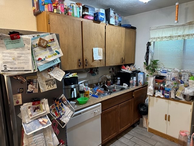 kitchen featuring sink, light hardwood / wood-style flooring, a textured ceiling, and dishwasher