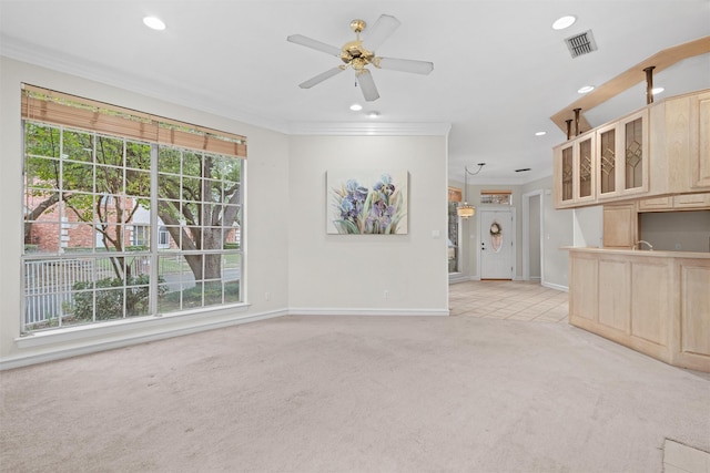 unfurnished living room featuring ornamental molding, light carpet, and ceiling fan