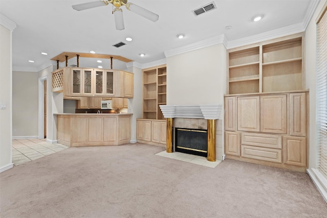 unfurnished living room featuring crown molding, light colored carpet, a tile fireplace, and ceiling fan