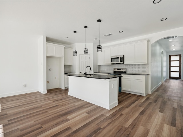 kitchen featuring a center island with sink, dark wood-type flooring, white cabinets, and stainless steel appliances