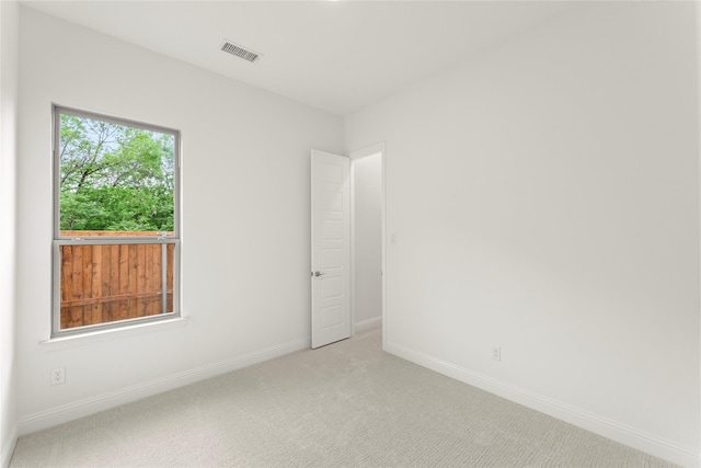 spare room featuring light colored carpet, visible vents, and baseboards