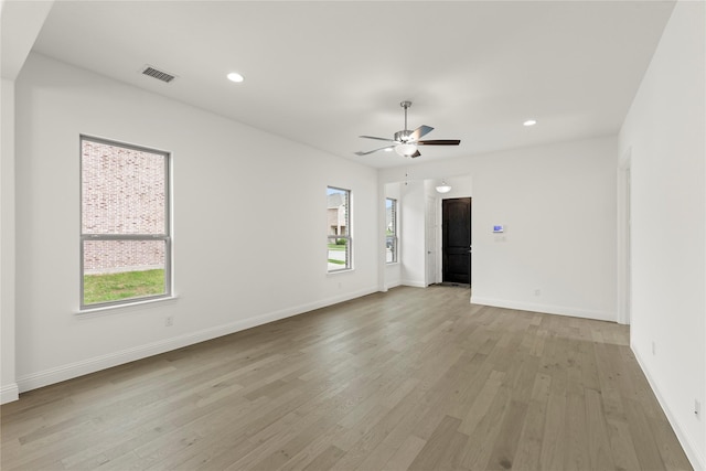 unfurnished room featuring light wood finished floors, visible vents, a ceiling fan, and a healthy amount of sunlight