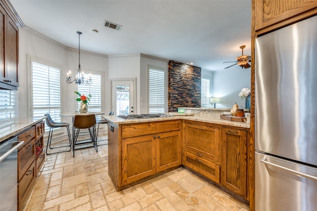 kitchen featuring appliances with stainless steel finishes, ceiling fan with notable chandelier, kitchen peninsula, hanging light fixtures, and ornamental molding