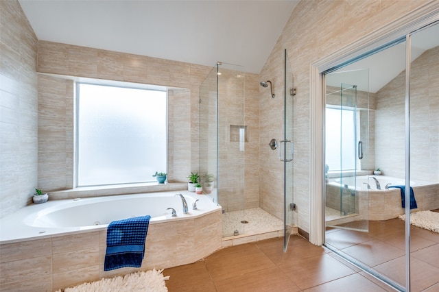 bathroom with a wealth of natural light, independent shower and bath, vaulted ceiling, and tile patterned flooring