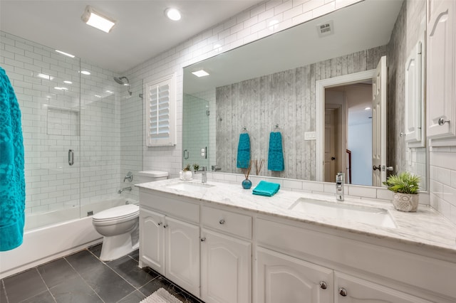 full bathroom featuring combined bath / shower with glass door, toilet, tile patterned floors, tile walls, and vanity