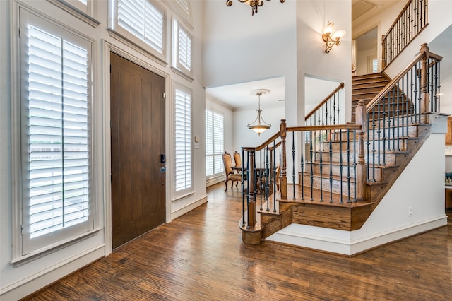 entrance foyer with a notable chandelier, dark hardwood / wood-style floors, and a towering ceiling