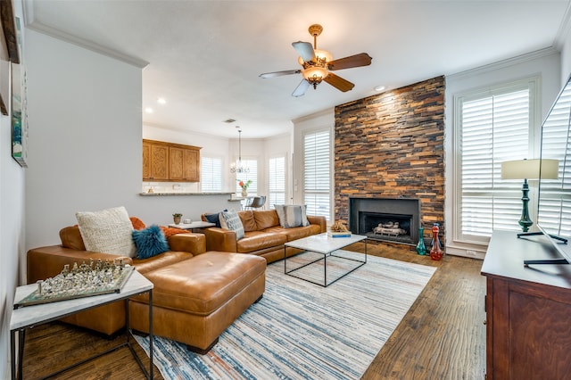 living room with crown molding, a healthy amount of sunlight, dark hardwood / wood-style floors, and a stone fireplace