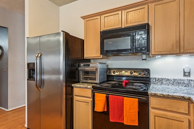 kitchen with a textured ceiling, light stone countertops, stainless steel appliances, and hardwood / wood-style flooring