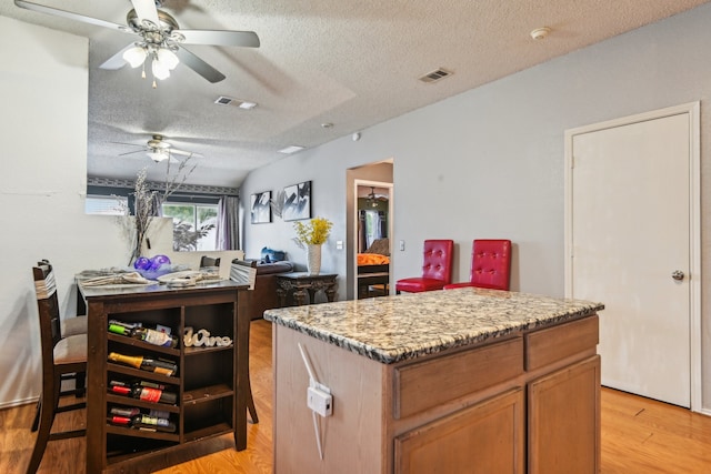 kitchen with a center island, a textured ceiling, light wood-type flooring, and ceiling fan