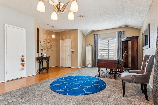 sitting room with lofted ceiling, hardwood / wood-style floors, a textured ceiling, and a notable chandelier