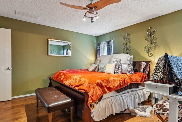 bedroom with a textured ceiling, hardwood / wood-style flooring, and ceiling fan