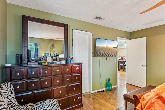 bedroom with light hardwood / wood-style floors and a textured ceiling