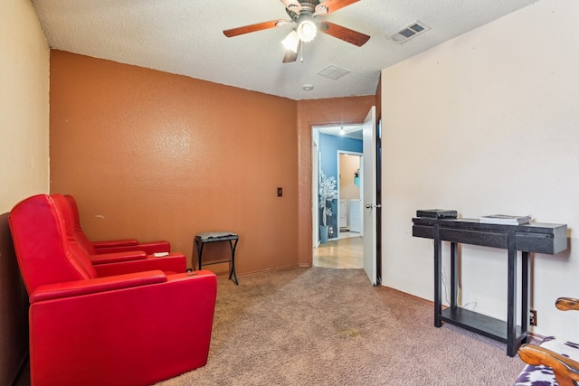 living area with light carpet, a textured ceiling, and ceiling fan