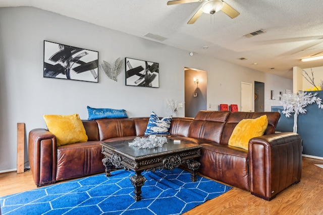 living room featuring a textured ceiling, wood-type flooring, and ceiling fan