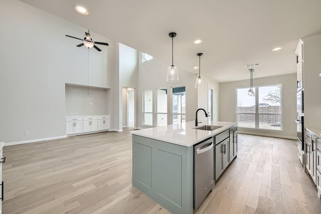 kitchen featuring sink, oven, hanging light fixtures, a kitchen island with sink, and stainless steel dishwasher