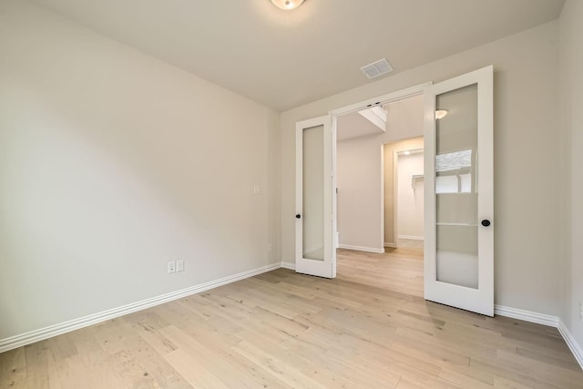 empty room with french doors and light hardwood / wood-style flooring