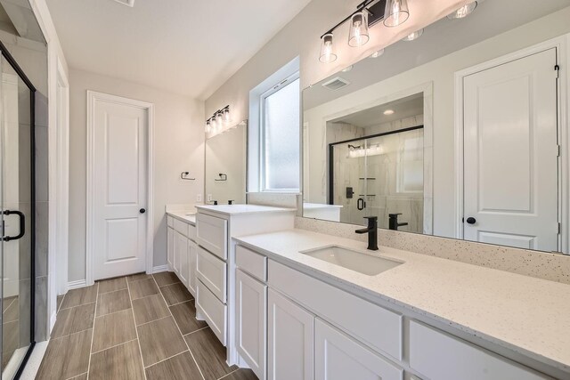 bathroom featuring a shower with door and vanity