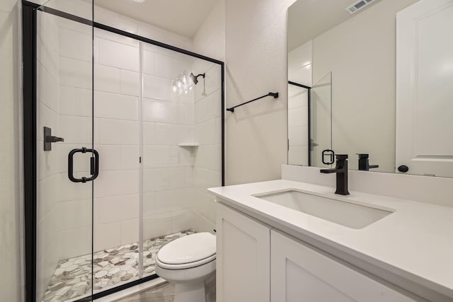 bathroom featuring vanity, an enclosed shower, and toilet