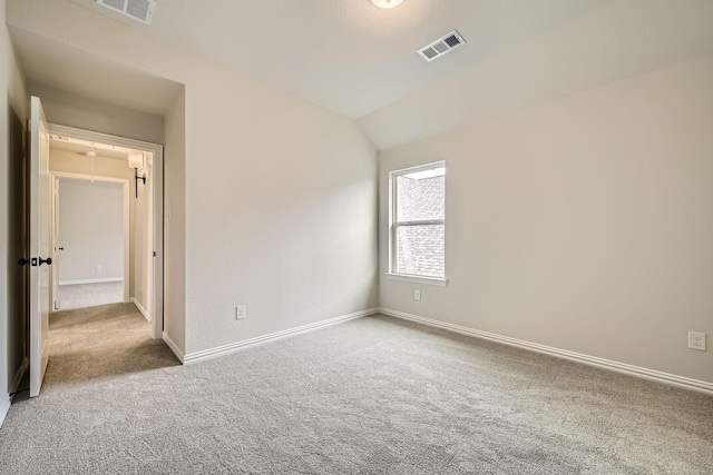 carpeted spare room featuring vaulted ceiling