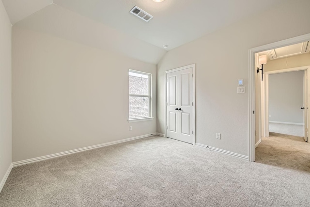 unfurnished bedroom with light colored carpet, vaulted ceiling, and a closet