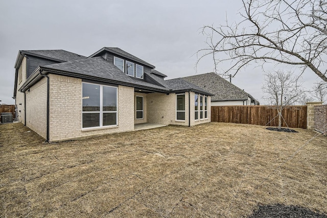 rear view of house featuring a yard, central AC unit, and a patio area