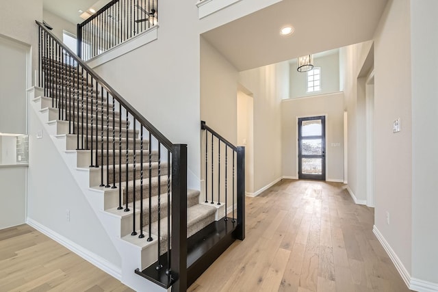 foyer entrance with a towering ceiling and light wood-type flooring