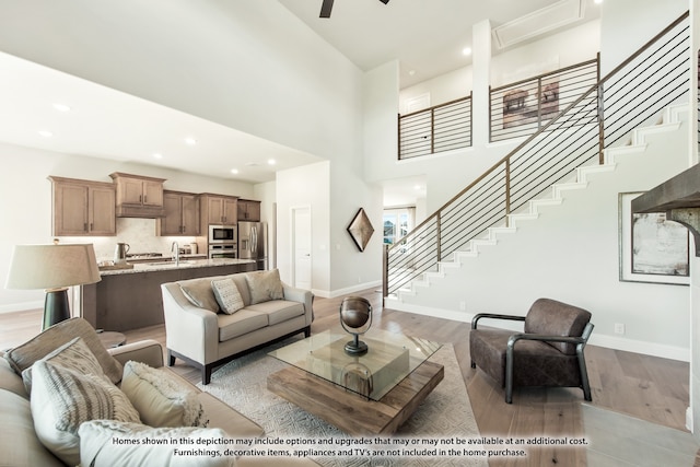 living room featuring sink, light hardwood / wood-style flooring, and a high ceiling