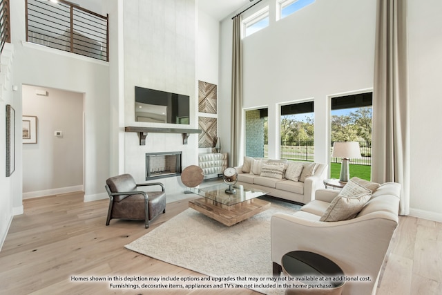 living room with light hardwood / wood-style floors, a high ceiling, and a wealth of natural light