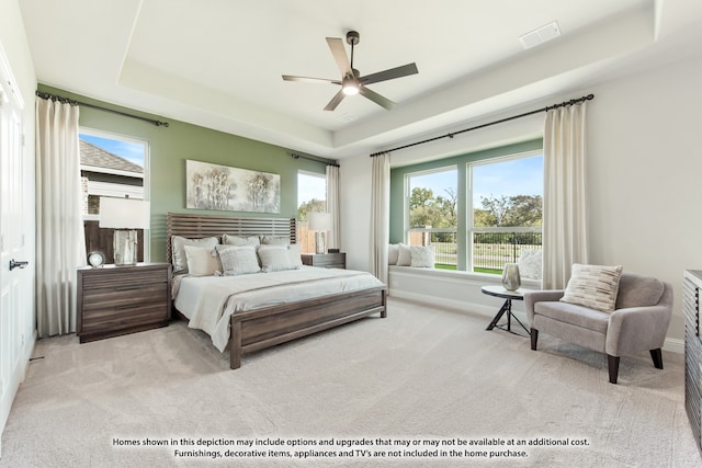 bedroom featuring light carpet, a tray ceiling, and ceiling fan