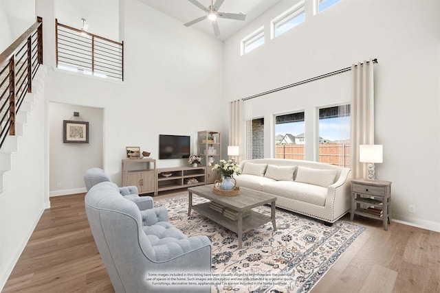 8924 New Ballinger Dr, Denton, TX 76226 - living area featuring baseboards, ceiling fan, stairway, wood finished floors, and a towering ceiling