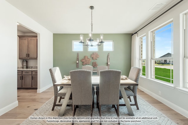 dining space with a notable chandelier, light hardwood / wood-style floors, and plenty of natural light