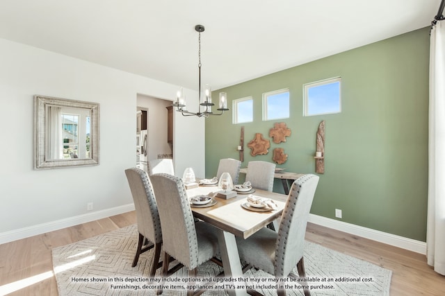 dining space with light hardwood / wood-style floors, a healthy amount of sunlight, and a chandelier