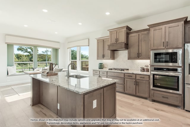 kitchen with sink, light hardwood / wood-style flooring, light stone counters, and stainless steel appliances