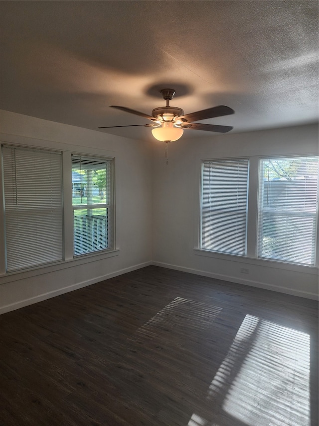 unfurnished room featuring ceiling fan, a textured ceiling, a healthy amount of sunlight, and dark hardwood / wood-style flooring