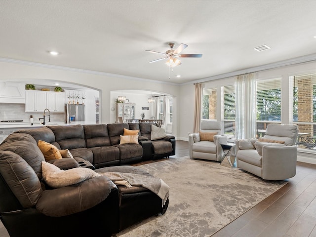 living room with crown molding, sink, hardwood / wood-style flooring, and ceiling fan with notable chandelier