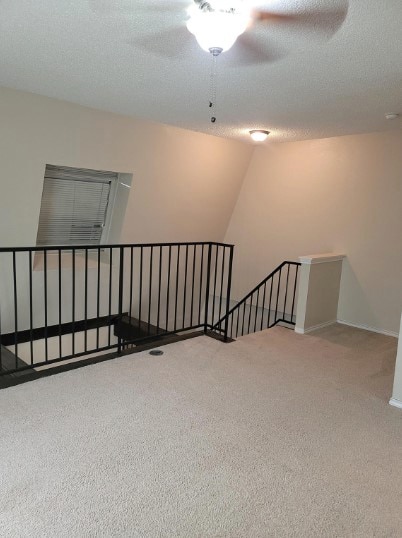 carpeted empty room featuring a textured ceiling and ceiling fan